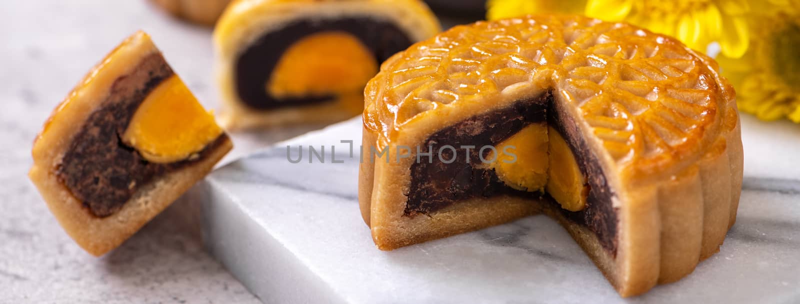 Tasty baked egg yolk pastry moon cake for Mid-Autumn Festival on bright cement table background. Chinese traditional food concept, close up, copy space.