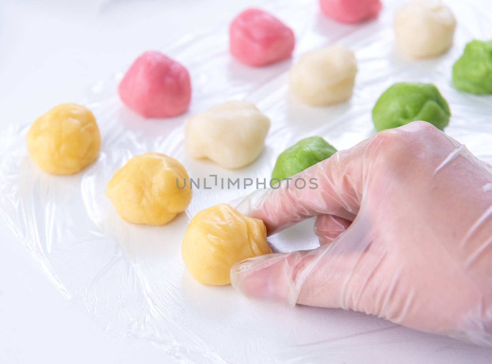 Young woman is making colorful snow skin moon cake, recipe of sweet snowy mooncake, traditional savory dessert for Mid-Autumn Festival, close up, lifestyle.