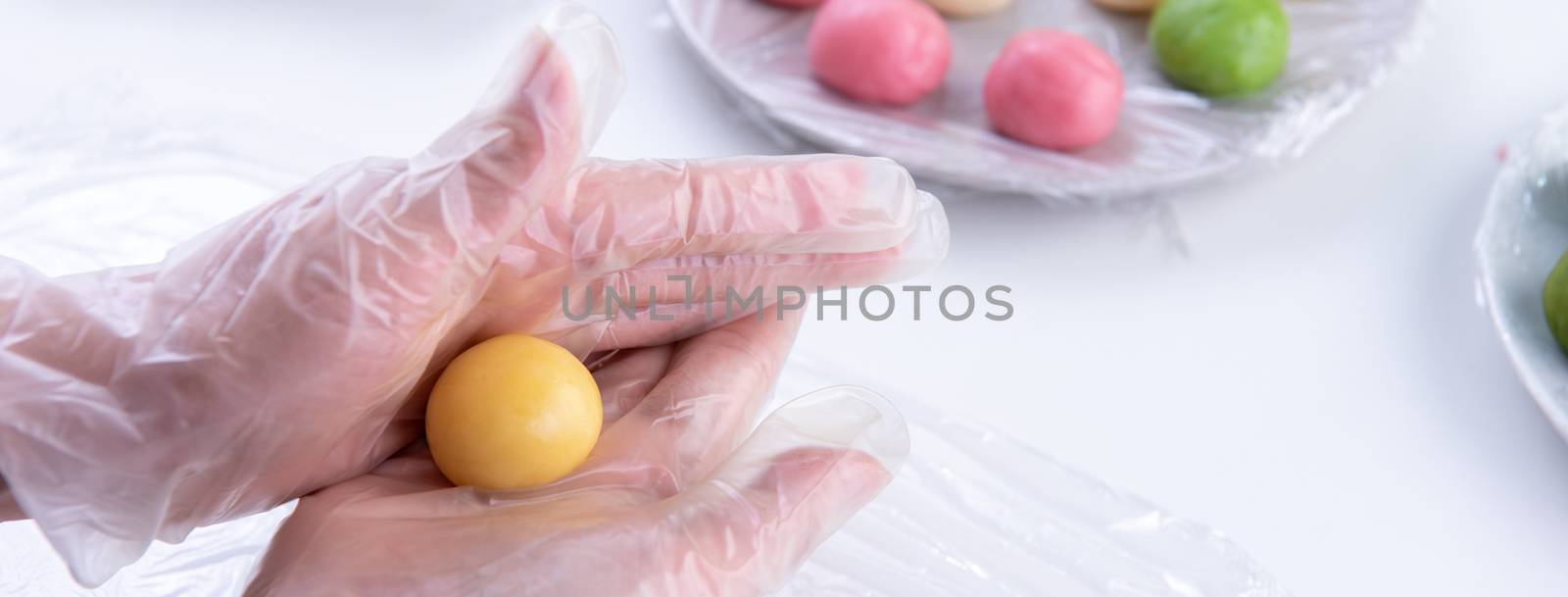 Young woman is making colorful snow skin moon cake, recipe of sweet snowy mooncake, traditional savory dessert for Mid-Autumn Festival, close up, lifestyle.