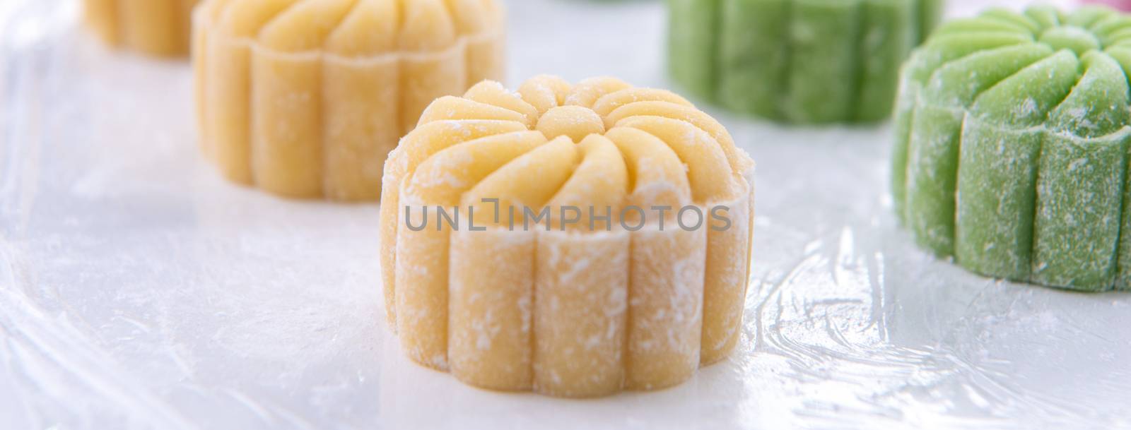 Young woman is making colorful snow skin moon cake, recipe of sweet snowy mooncake, traditional savory dessert for Mid-Autumn Festival, close up, lifestyle.