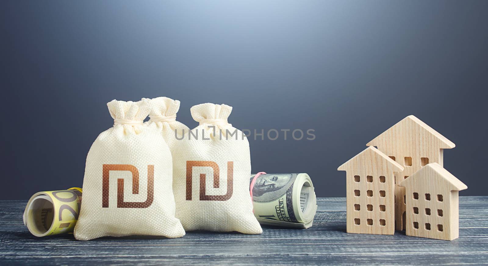 Israeli shekel money bags and residential buildings figures. Financing the construction of new settlements. Municipal budget management. Investments in real estate. Mortgage loan. Taxes.