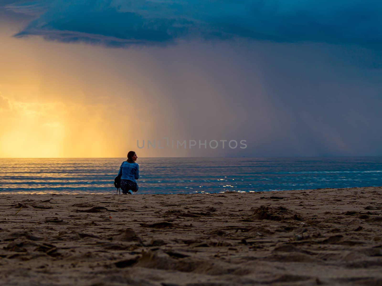 beautiful alone girl on the beach. Girl looking at stormy sea amd taking a picture with smarphone. The spectacular Storm with rain Is Coming in Estonia. Baltic sea