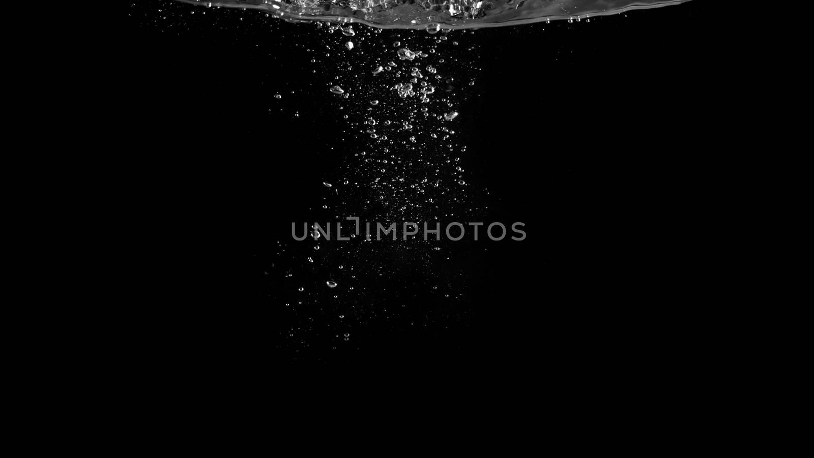 Close-up macro images of soda water bubbles floating up to top of water surface which little and big circle texture splashing up by gas power in carbonate drink make refreshing moment on black background.