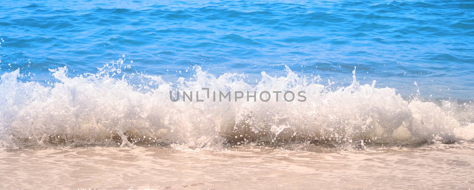 Clear light blue color sea water or liquid marine waving and splashing to light brown color sand beach on summer day in Pattaya Thailand and no people swimming because of hot weather.