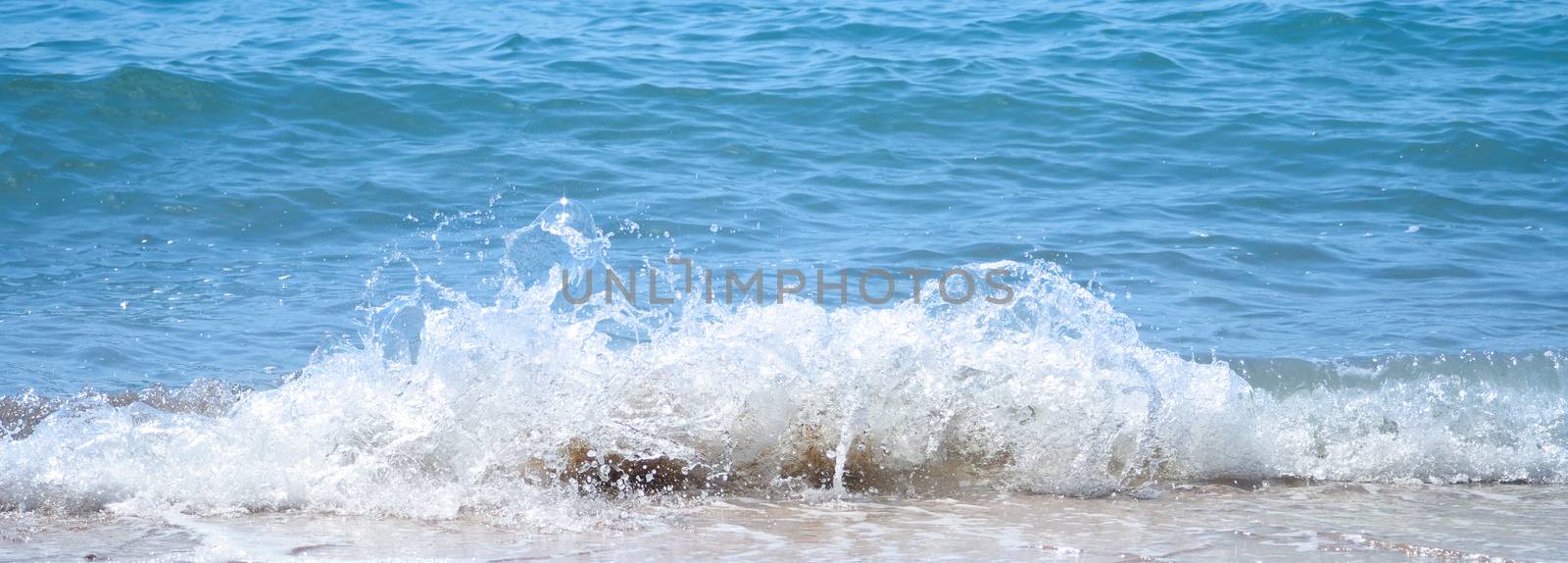 Clear light blue color sea water splashing to beach by gnepphoto