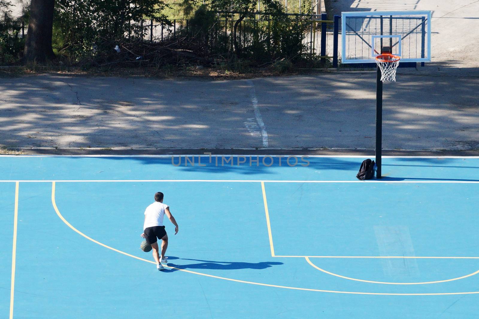 Varna, Bulgaria - August, 22, 2020: young man training with a ball on an outdoor basketball court