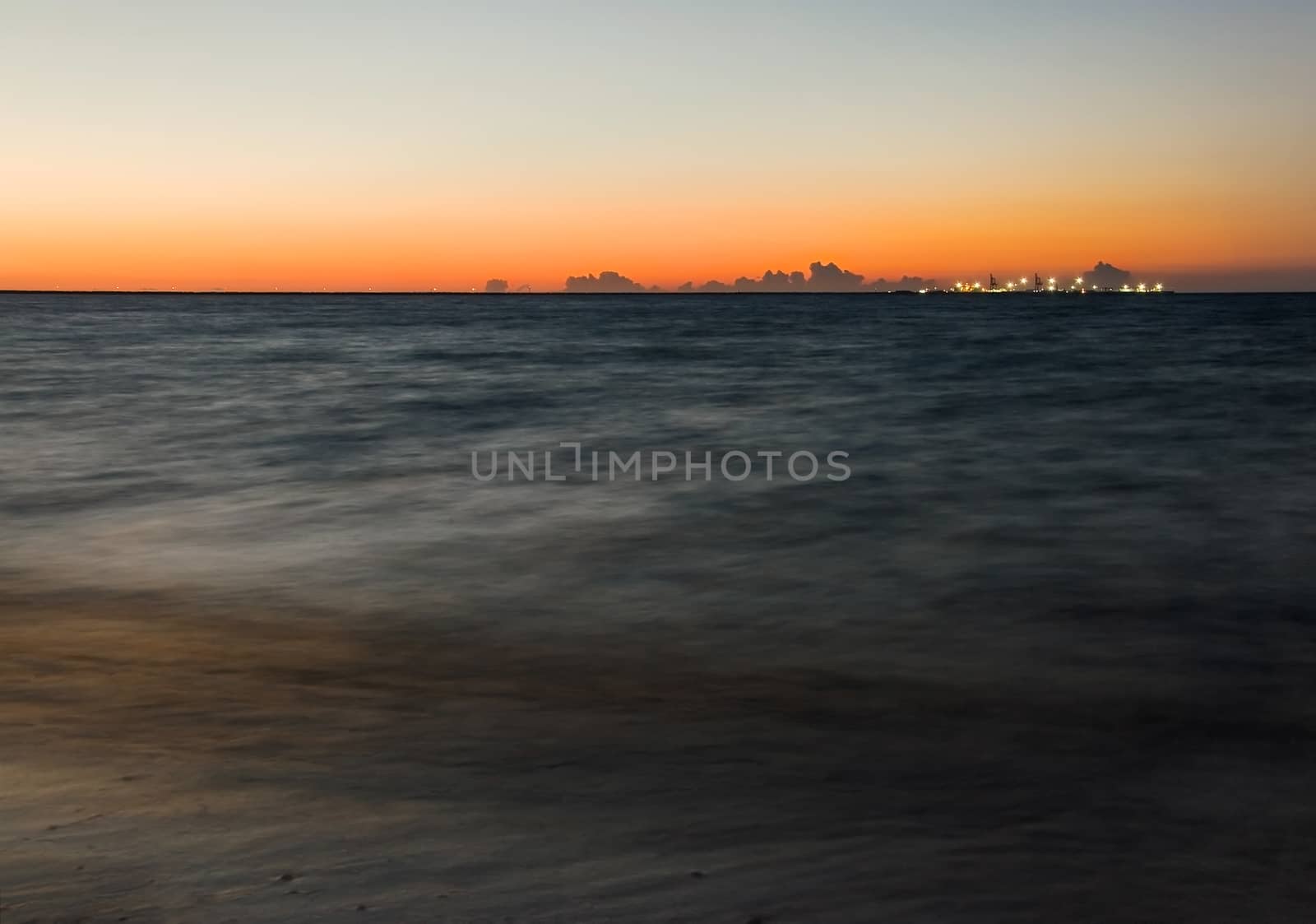 Long exposure shot of dark sea with ships pier illuminated by li by Ivanko