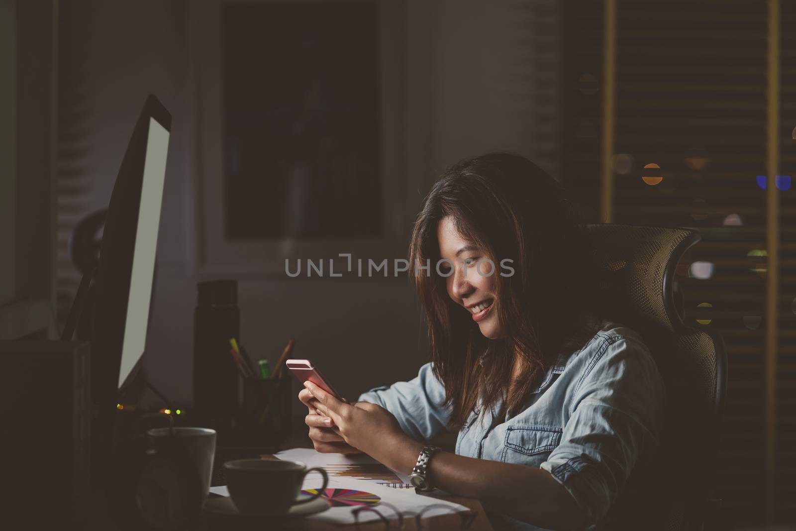 Portrait of Asian Businesswoman sitting and working hard with happiness action on the table with front of computer desktop in workplace at late time, Work hard and too late concept