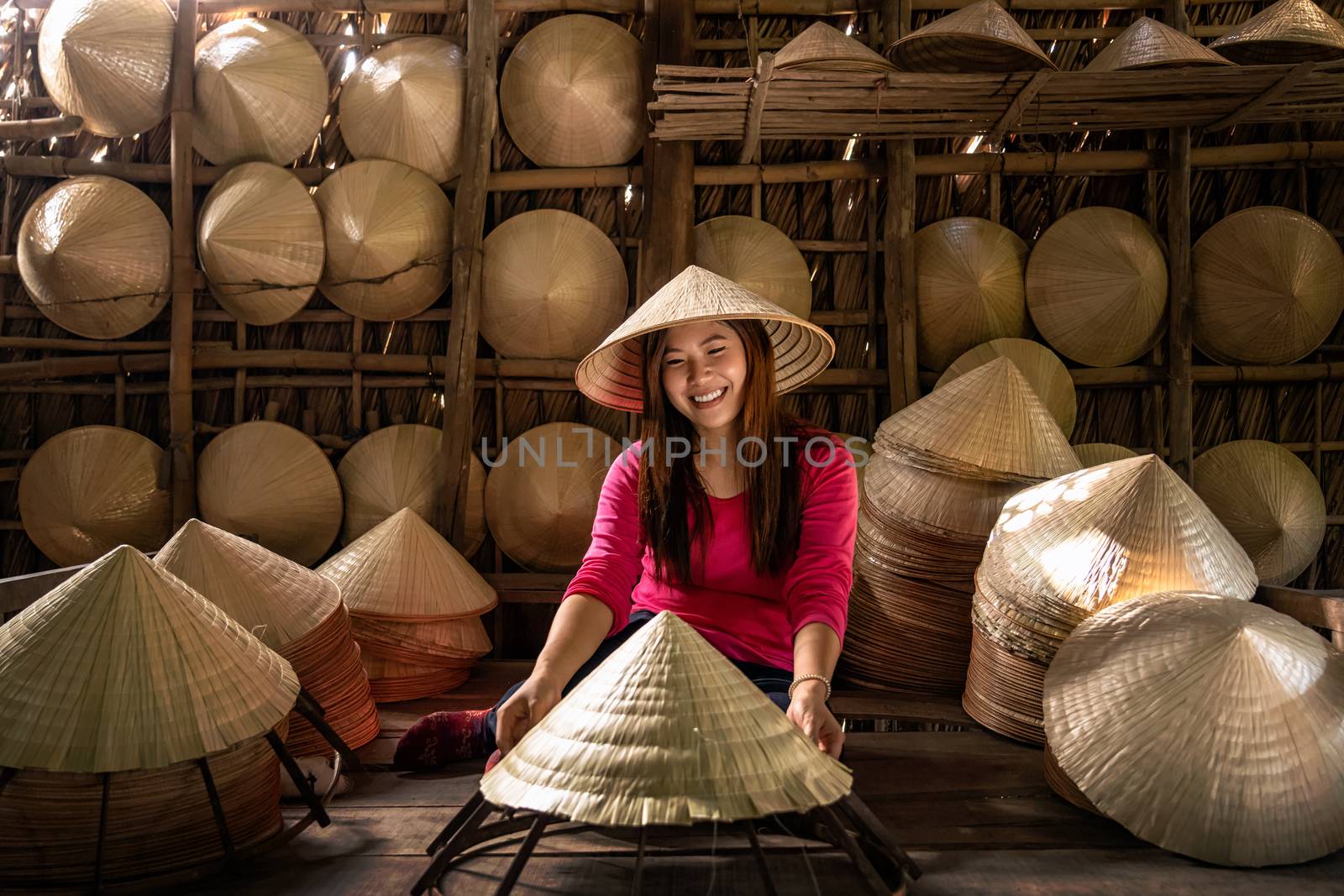 Asian traveler female craftsman making the traditional vietnam hat in the old traditional house in Ap Thoi Phuoc village, Hochiminh city, Vietnam, traditional artist concept
