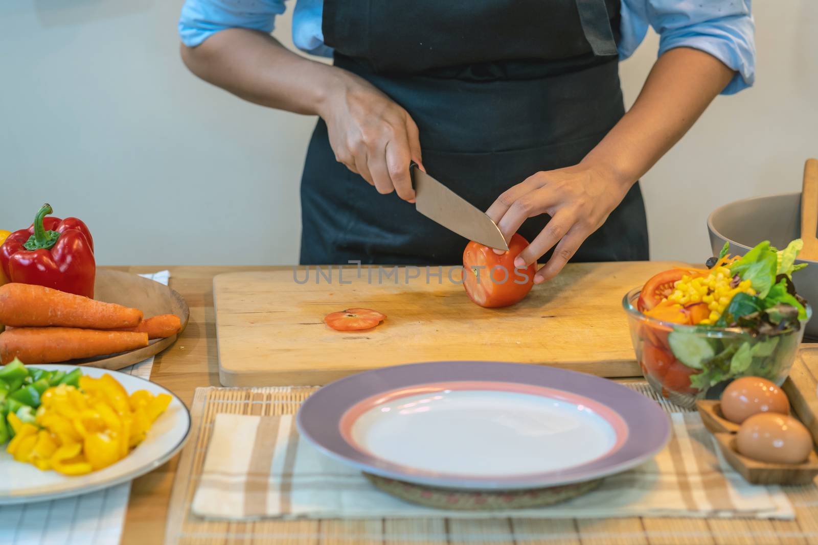 Closeup chef hand cutting the tomato on the Chopping board in modern kitchen, diet and healthy food concept