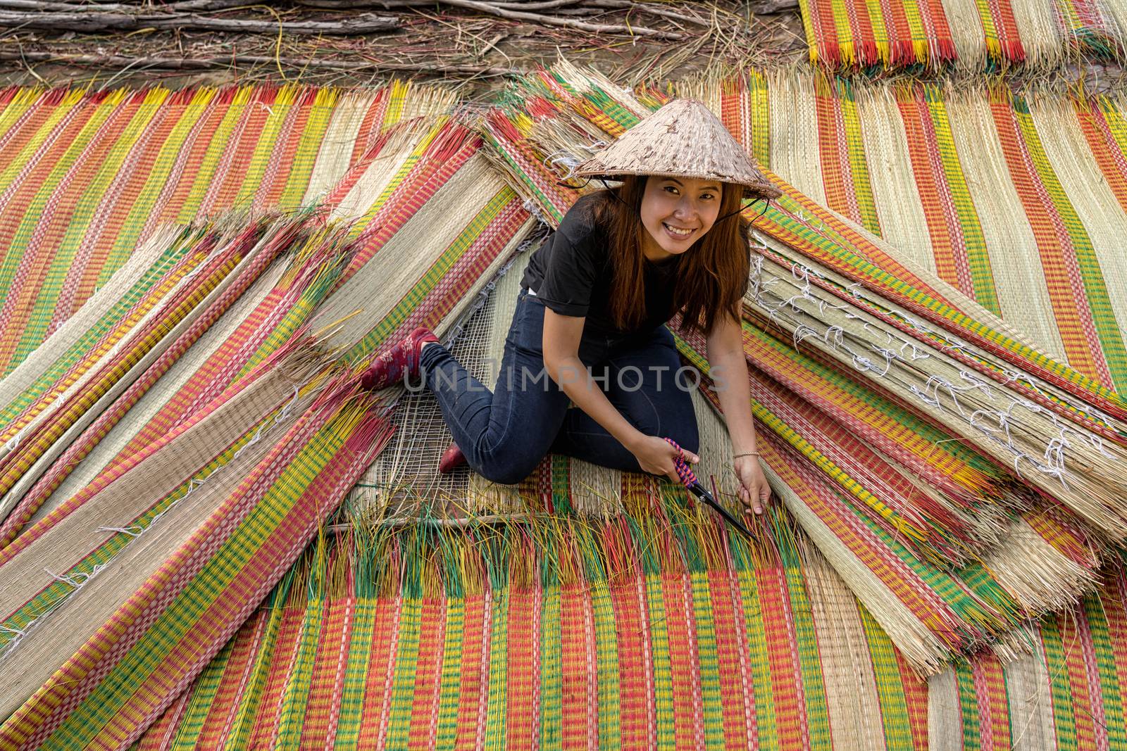 Top view of young Vietnamese craftsman making the traditional vietnam mats with happiness action in the old traditional village at dinh yen, dong thap, vietnam, tradition artist concept