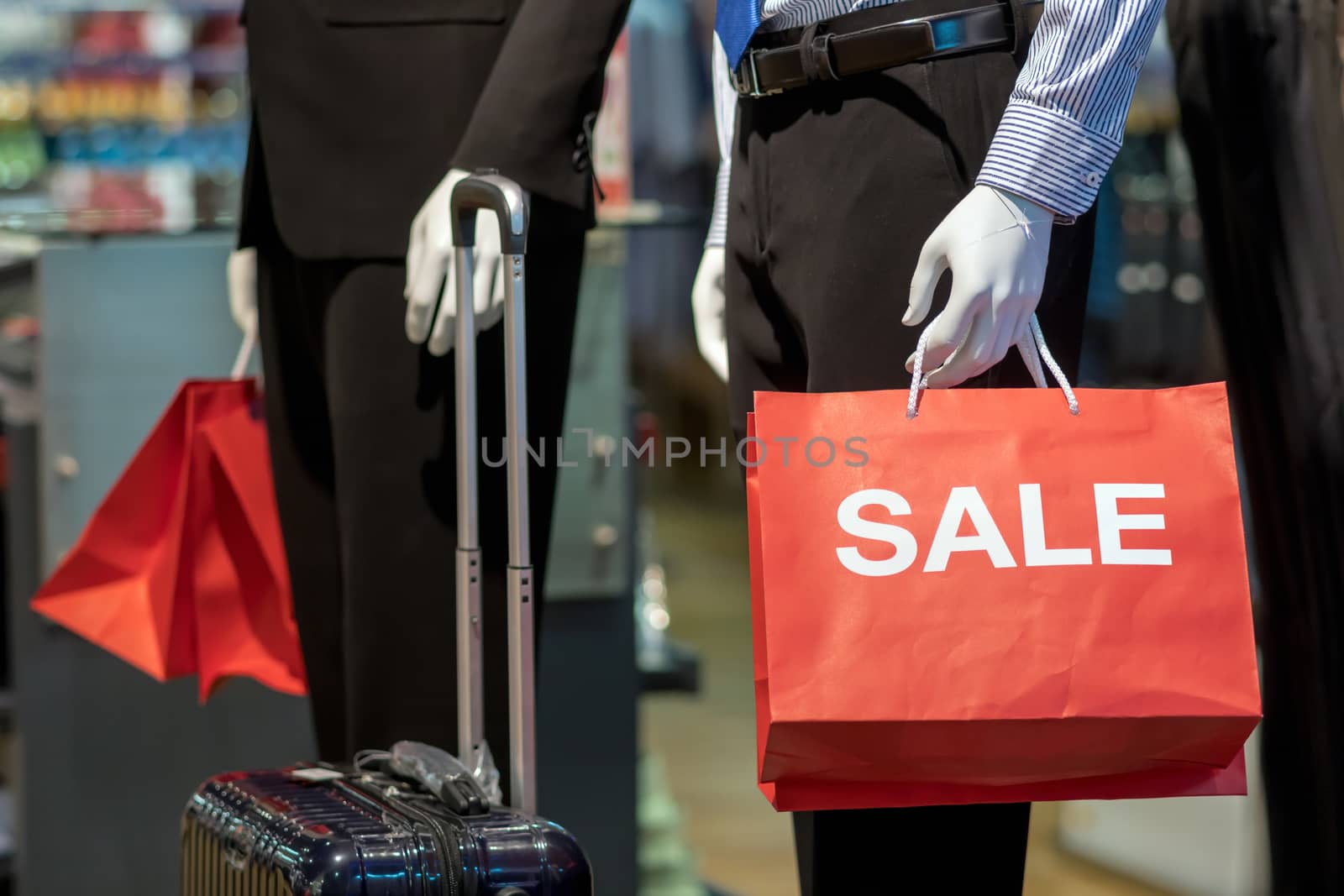 Part of male mannequin dressed in business formal suit holding the Sales paper shopping bag in the shopping department store for shopping, business fashion and advertisement concept