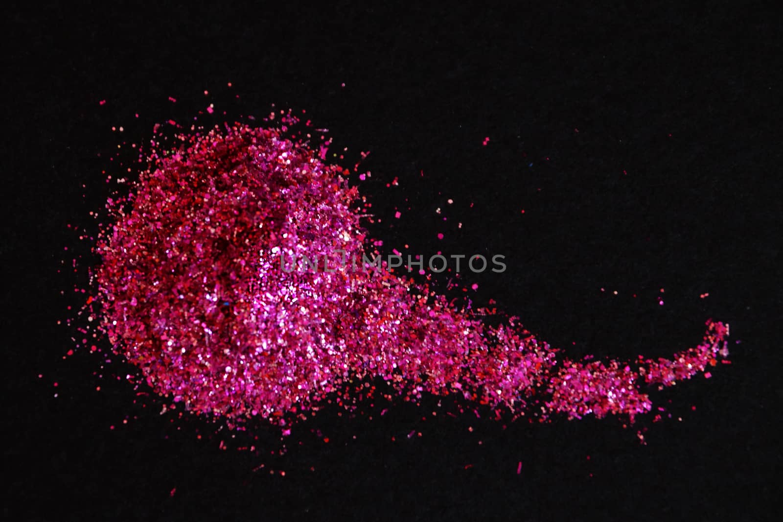 scattering of dark pink shiny glitter on a black background, copy space,