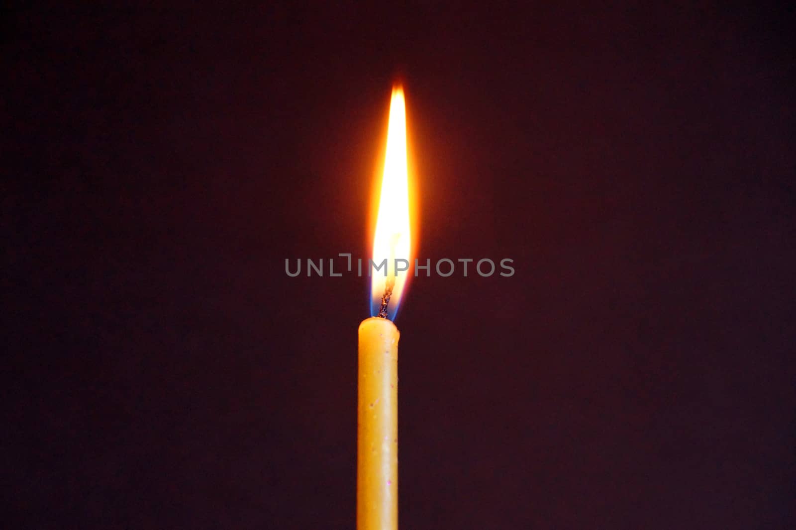 burning wax candle close up on dark background by Annado