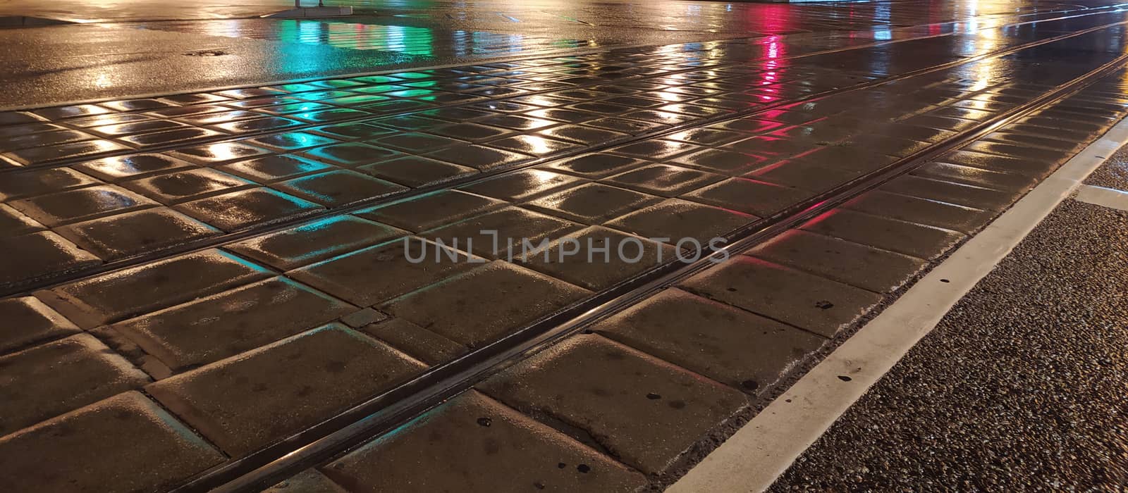 pavement wet from the rain with reflective lights in the evening by Annado