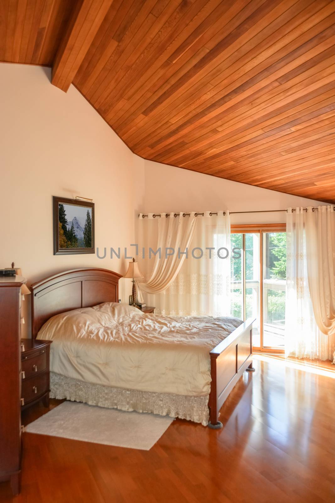 Beautiful bedroom with wooden ceiling and sun light coming through glass door