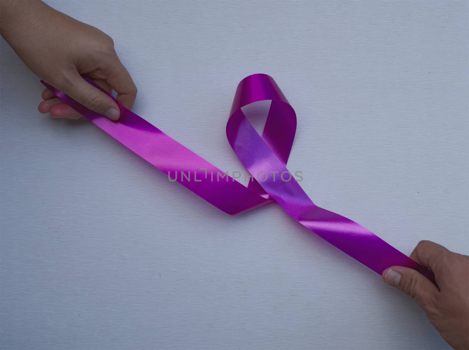 Abstract women hands and men hands pulling pink ribbons expressing breast cancer awareness day concept isolated pink background.