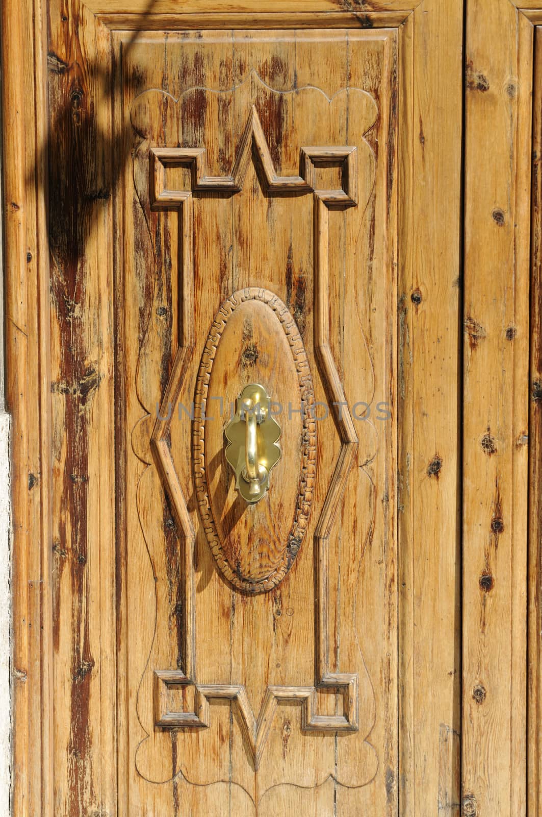 Close-up view of a wooden door with old-fashioned door knocker made of brass.