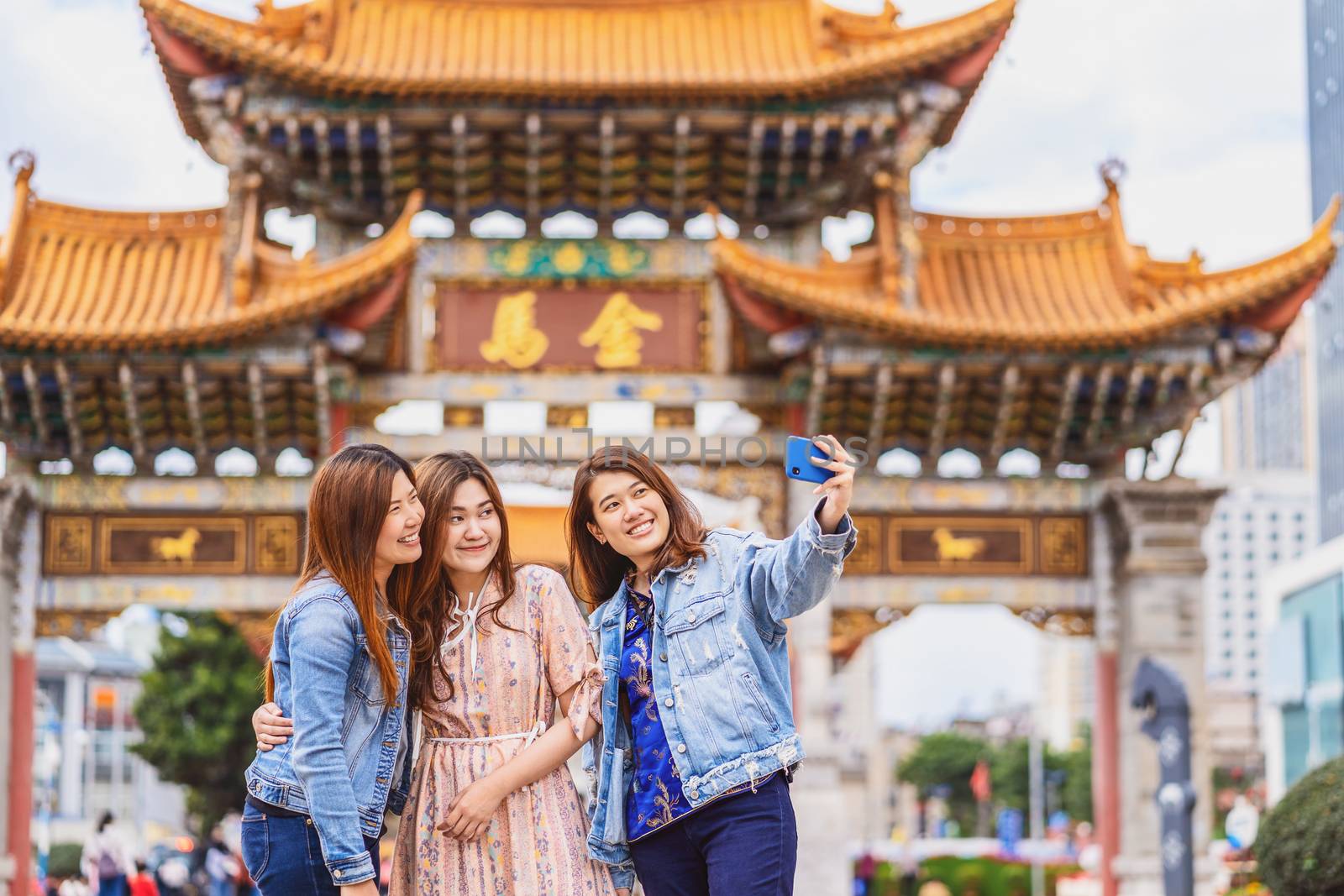 Portrait Three asian happiness women using smart mobile phone for selfie together when travelling over the Jinbi square, Kunming, China, travel and tourism with friendship concept