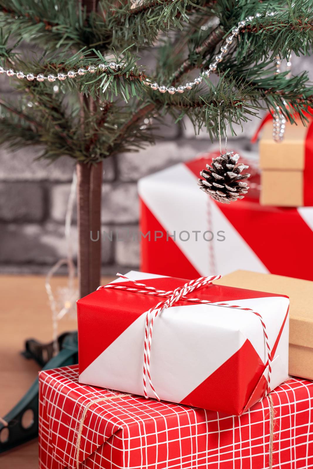 Decorated Christmas tree with wrapped beautiful red and white gifts at home with black brick wall, festive design concept, close up.