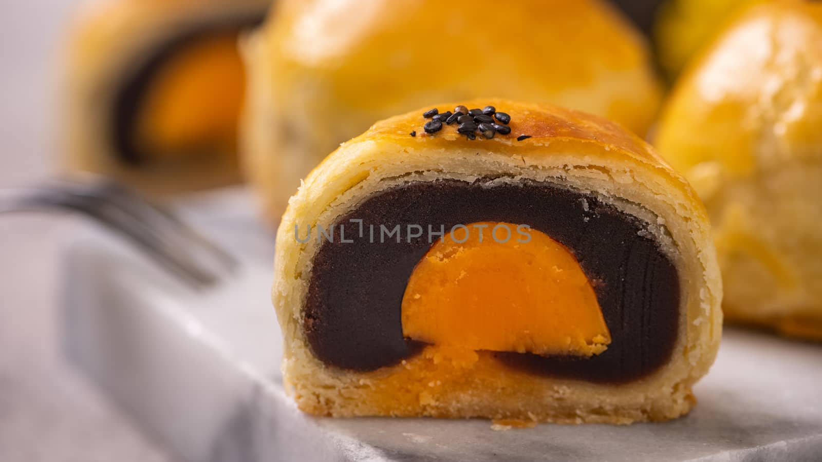 Tasty baked egg yolk pastry moon cake for Mid-Autumn Festival on bright cement table background. Chinese traditional food concept, close up, copy space.