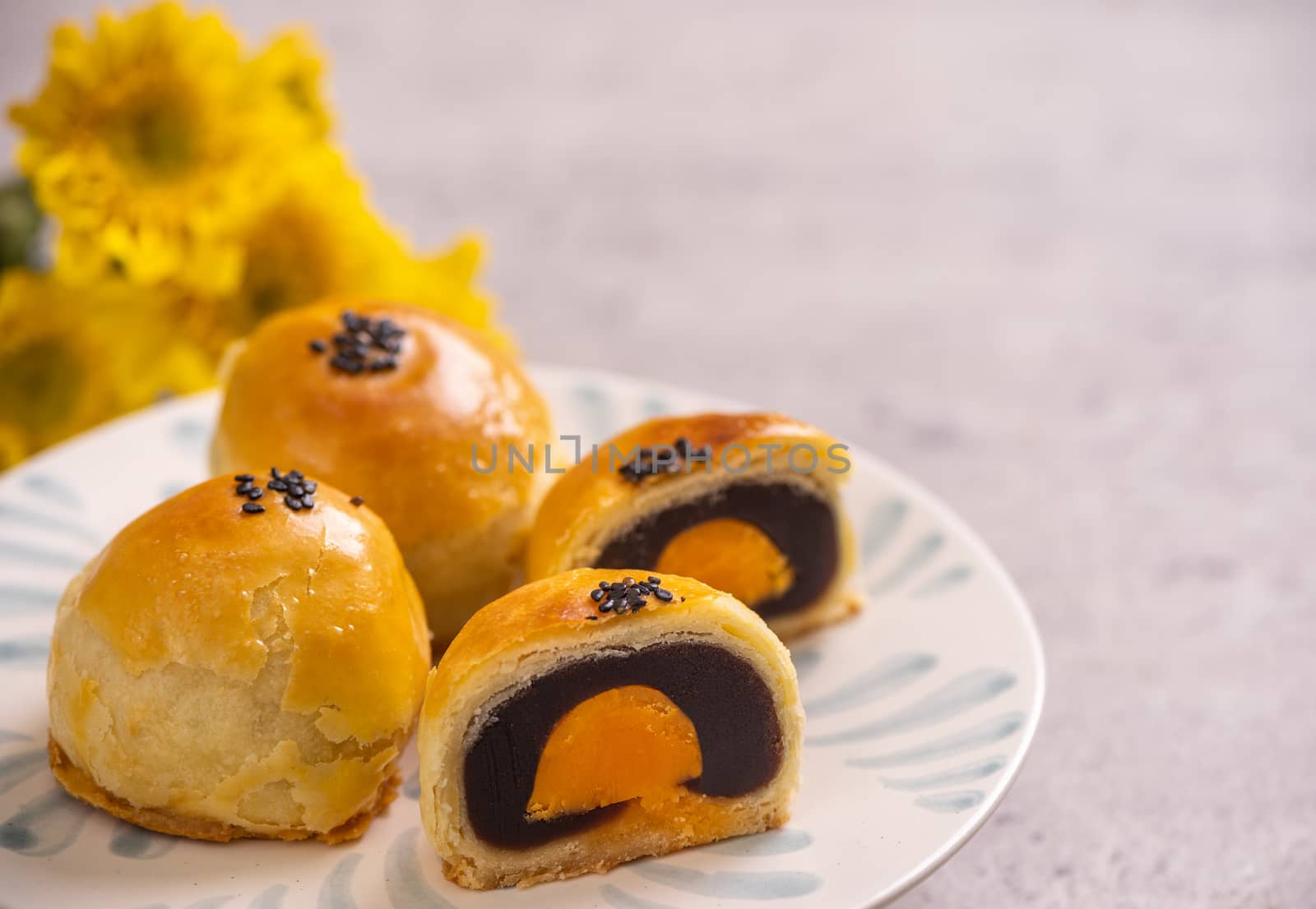 Tasty baked egg yolk pastry moon cake for Mid-Autumn Festival on bright cement table background. Chinese traditional food concept, close up, copy space.