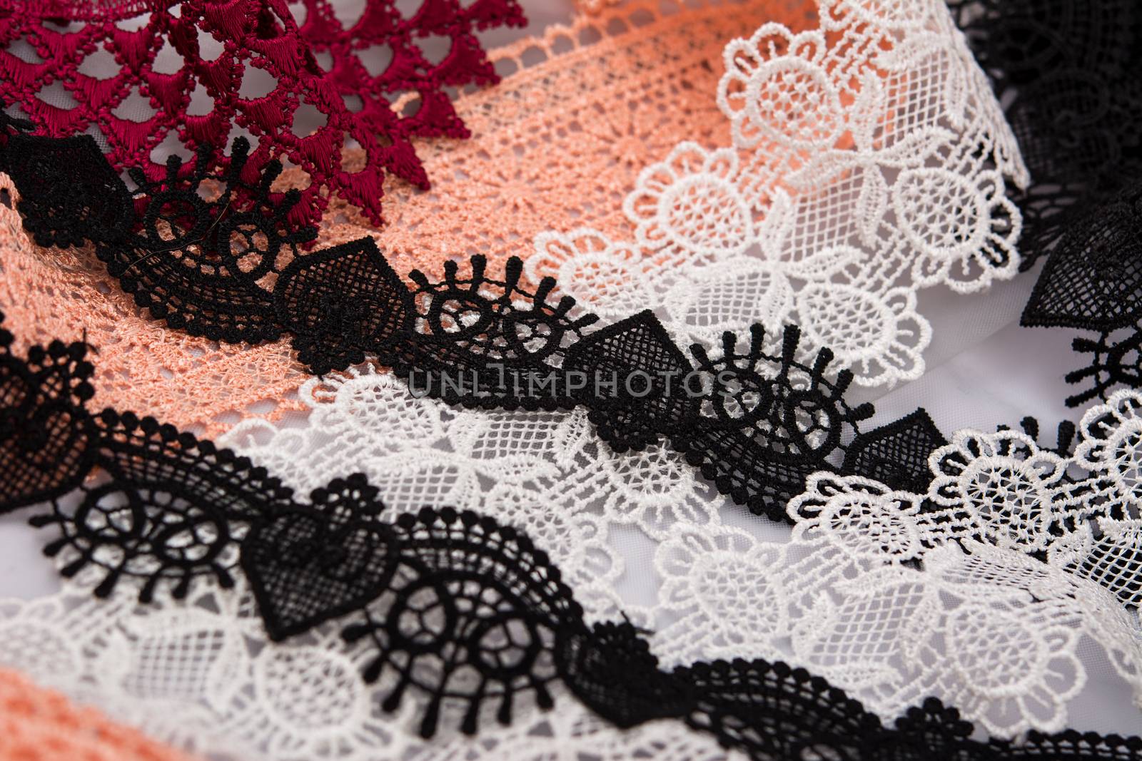 pile of orange, red, white. and black gentle luxury quality guipure, lace fabric. use for sew clothes linen decoration. texture for websites. Space for text.