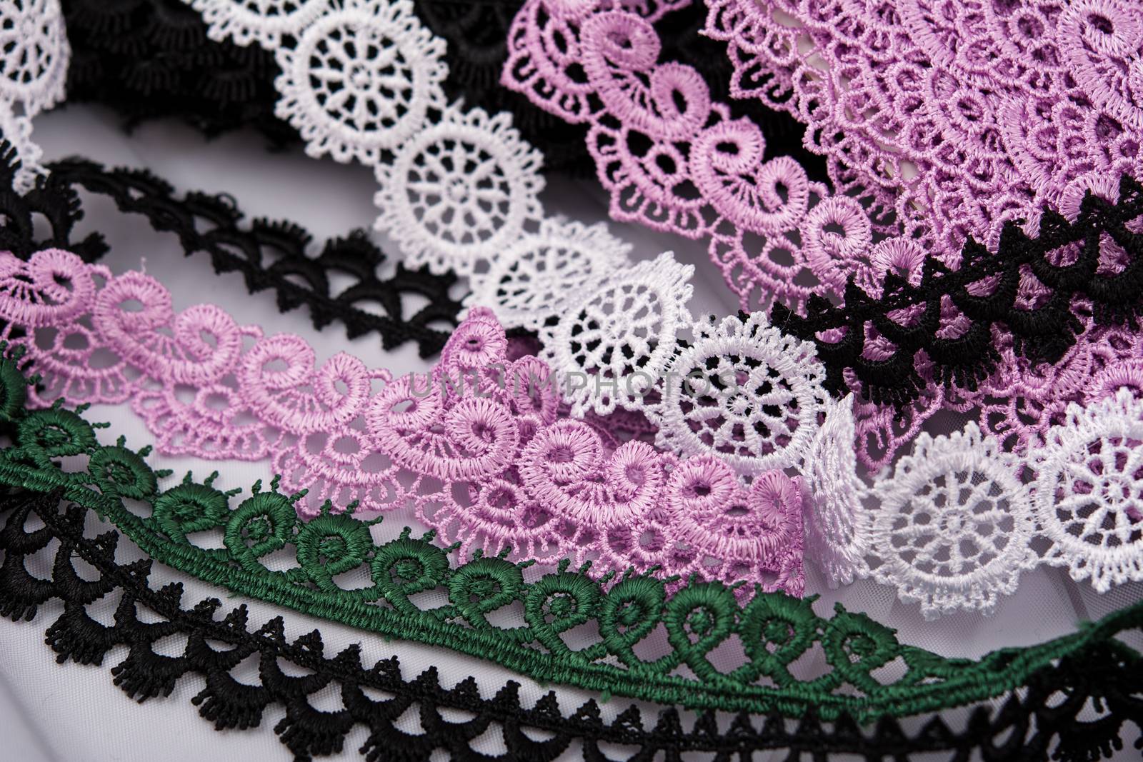 pile of purple, green, white and black gentle luxury quality guipure, lace fabric. use for sew clothes linen decoration. texture for websites. Space for text.