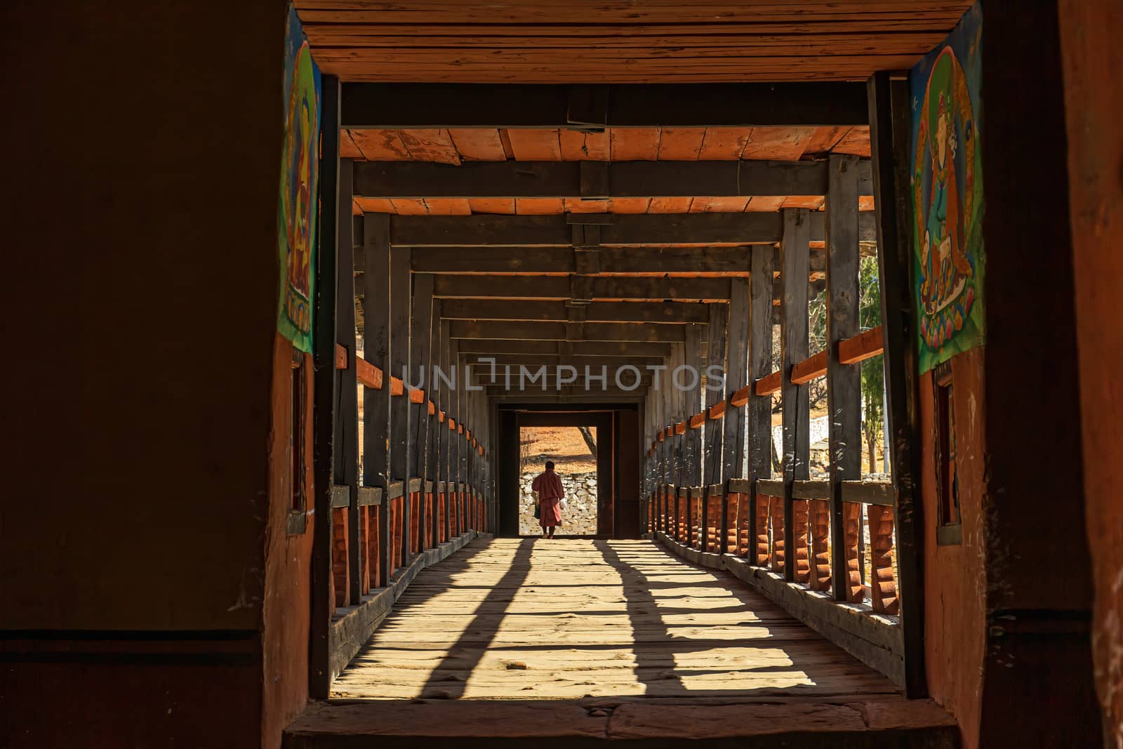 Monk walking over wooden bridge