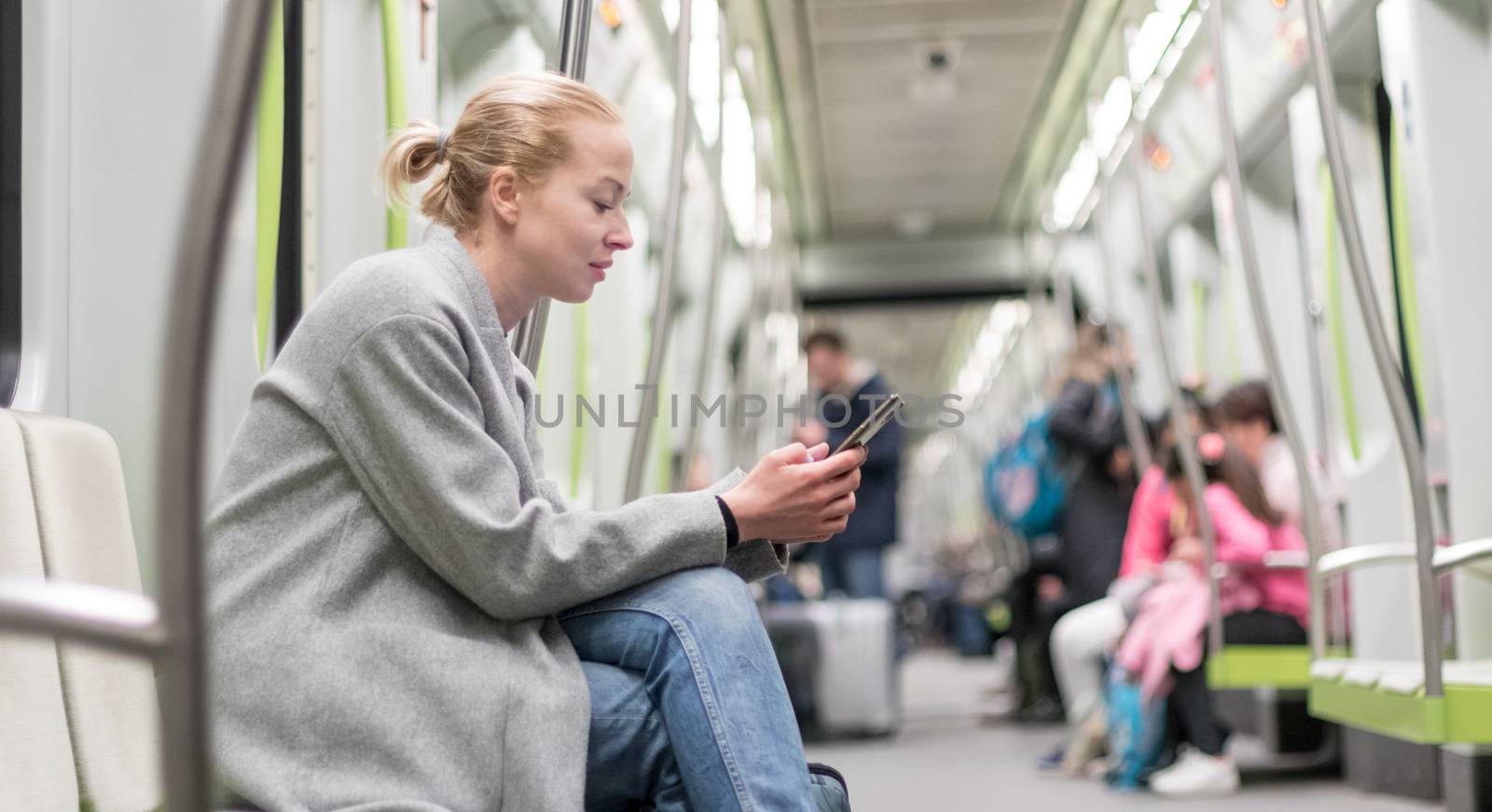 Portrait of lovely girl typing message on mobile phone in almost empty public subway train. Staying at home and social distancing recomented due to corona virus pandemic outbreak.