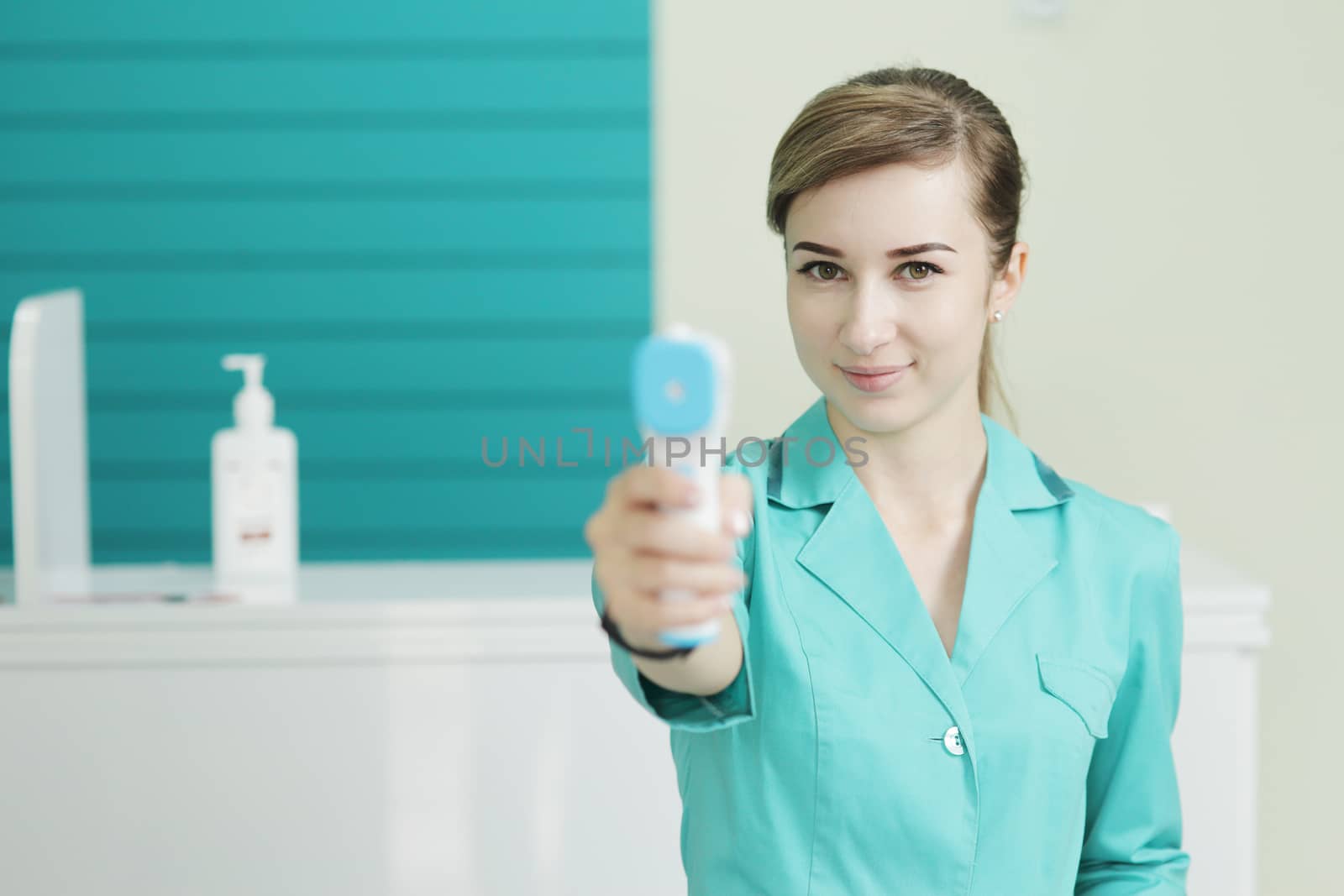 Female doctor or nurse at hospital holds pyrometer in hand. Safety measures against the coronavirus. Prevention Covid-19 healthcare concept. Stethoscope over the neck.