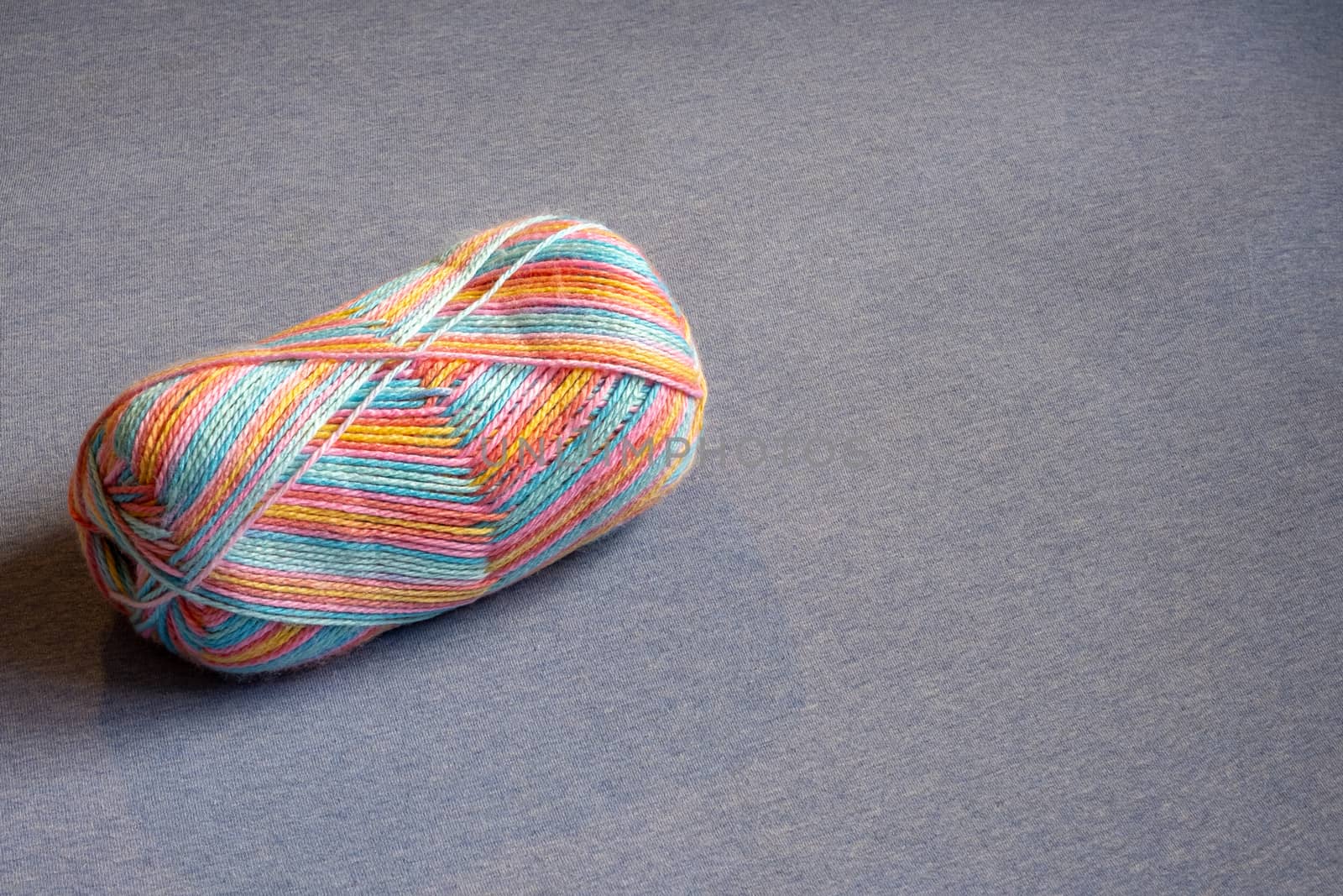 A skein of brightly-colored yarn has pink, blue and yellow coloring in a variety of shades.