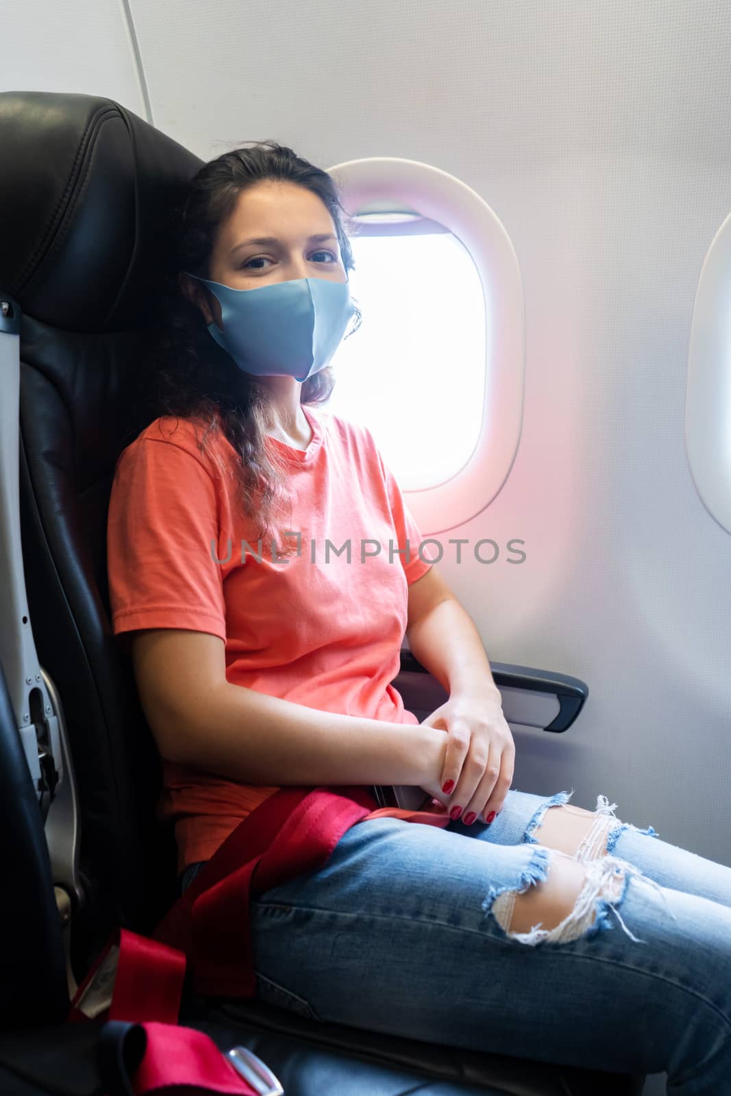 A girl in a medical mask on her face during a flight in the cabi by Try_my_best