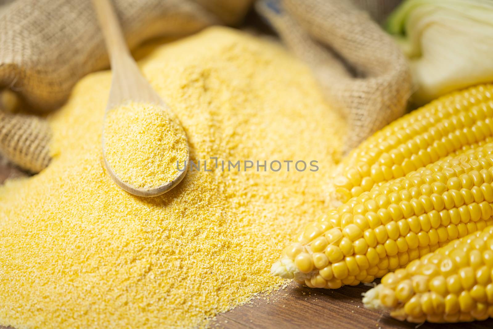 Ripe young sweet corn cob spoon and cornmeal close up by Robertobinetti70