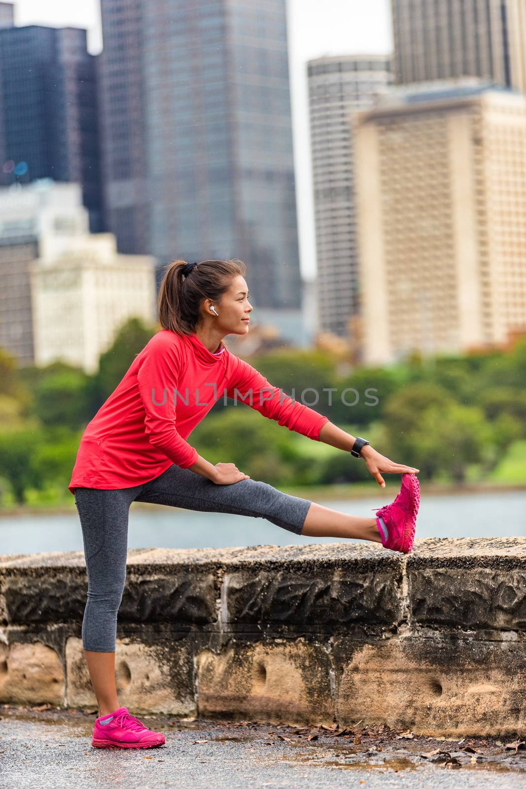 City running healthy lifestyle runner woman stretching legs exercise to run in urban background. Sydney, Australia travel. Asian sport girl by Maridav