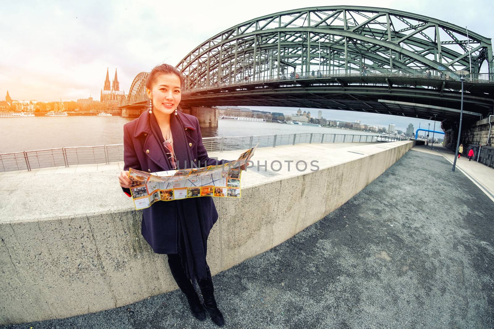 Yound beautiful looking a map and view of river with beautiful Cologne Cathedral in Germany
