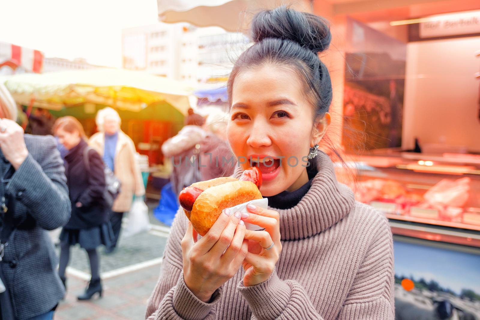 Young Woman Eating A Hotdog Street food in Germany by Surasak