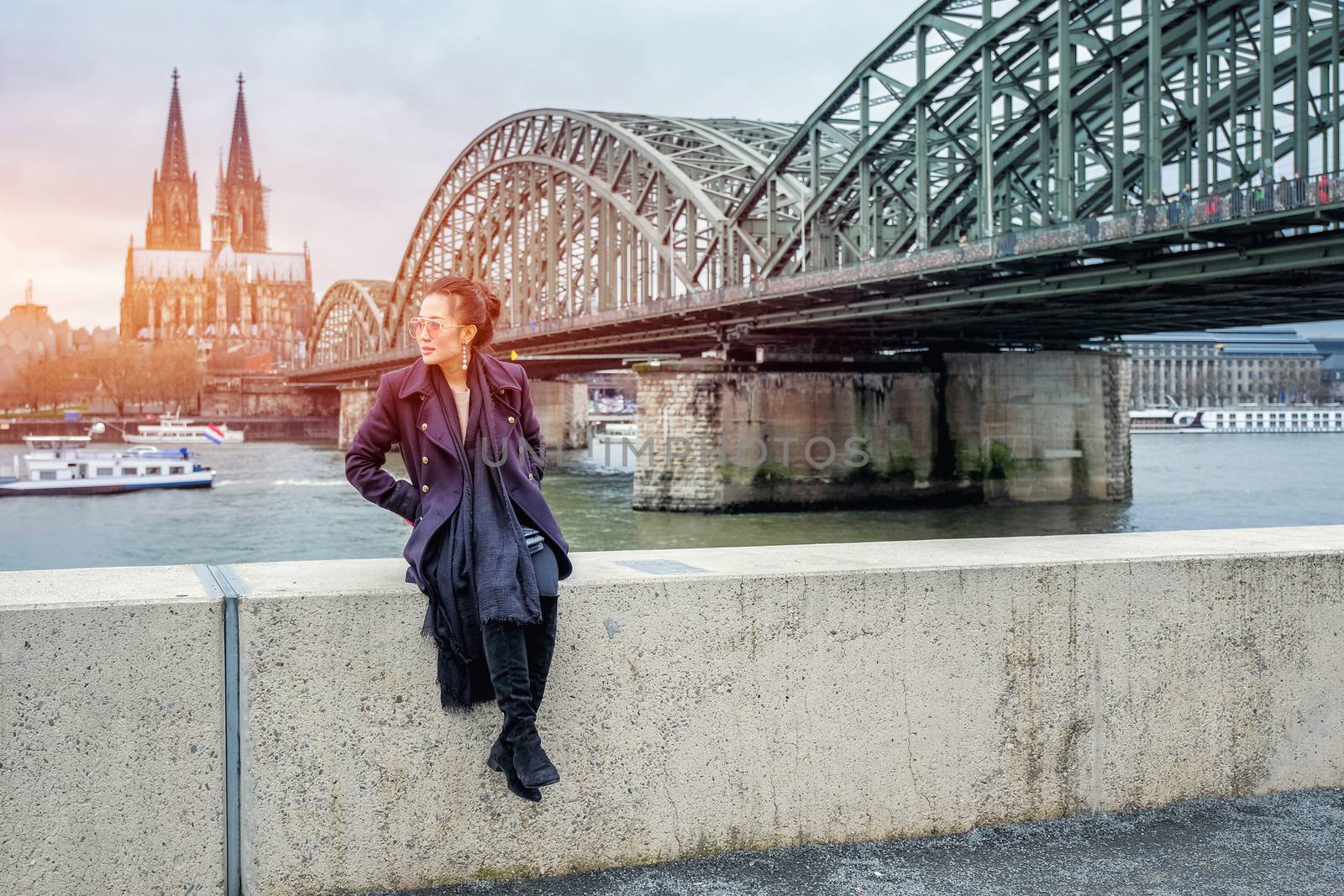 Yound beautiful woman sitting by the river with beautiful Cologne Cathedral in Germany
