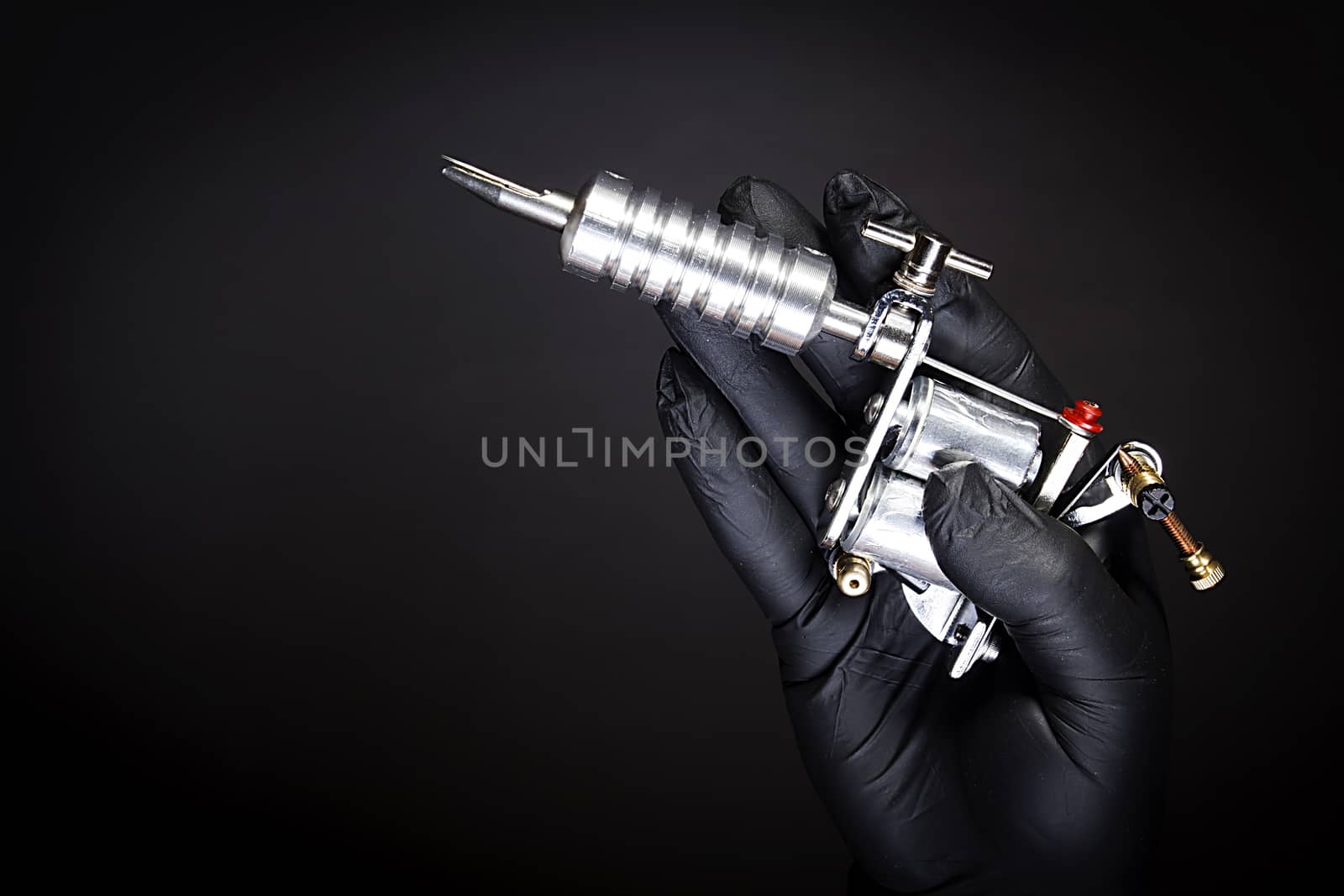 Tattoo machine in artist’s hand isolated on black background
