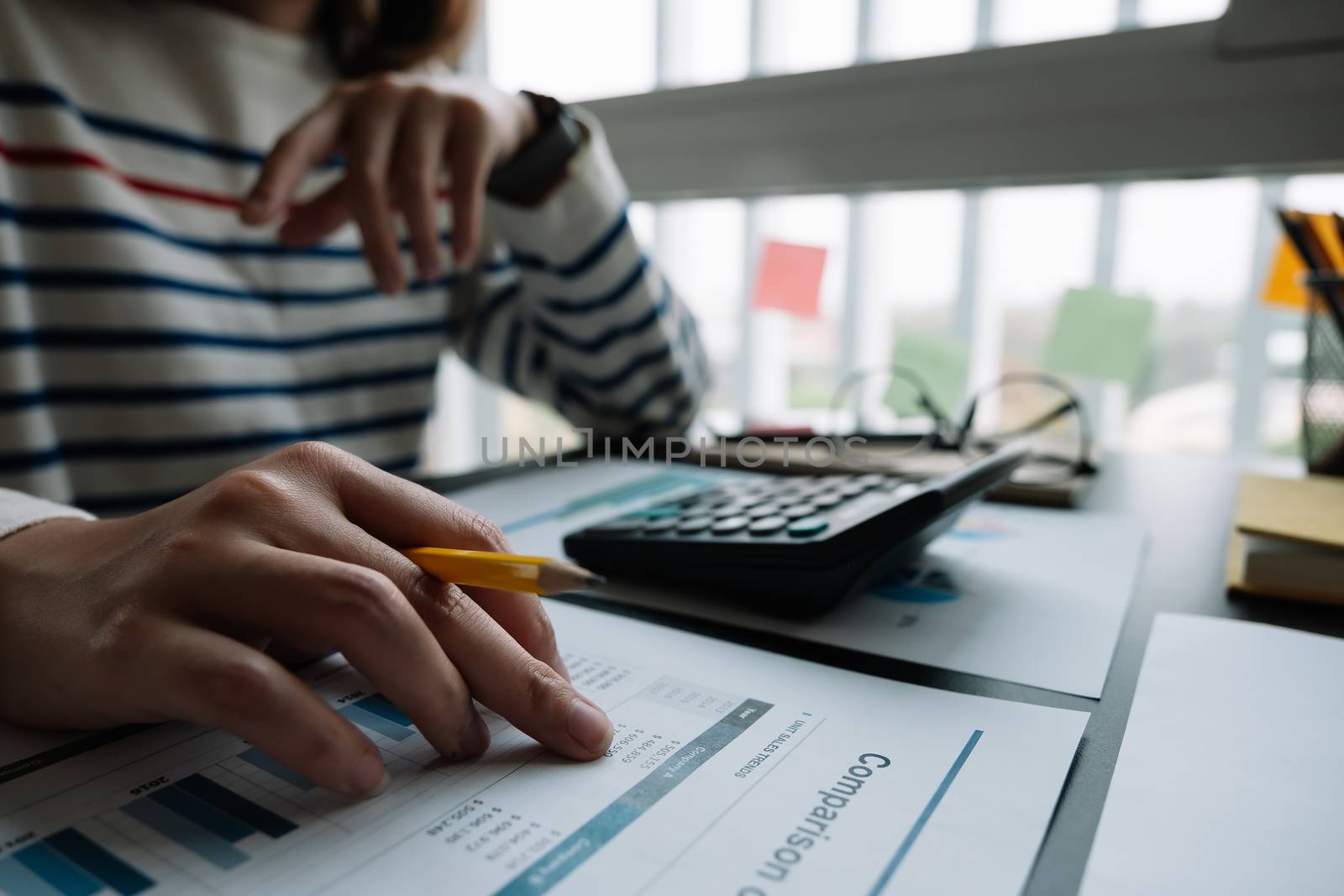 Business woman working in finance and accounting Analyze financial budget with calculator in the office.