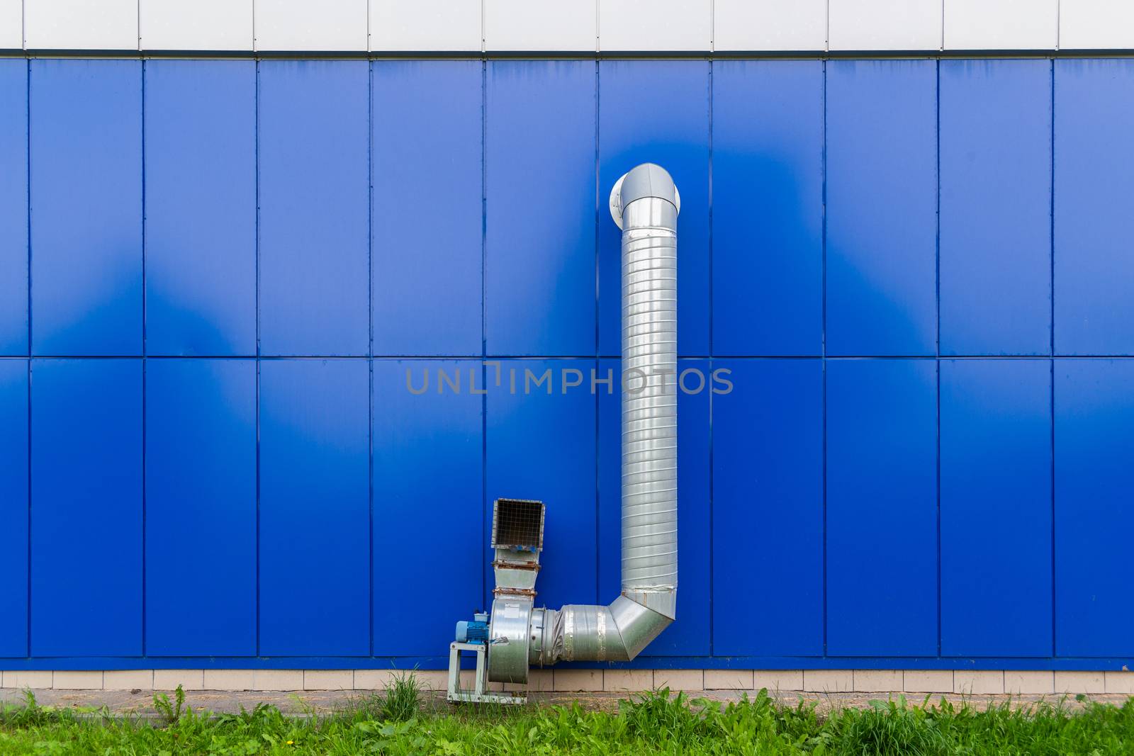 industrial grade air extraction duct with electrical motor on blue wall.