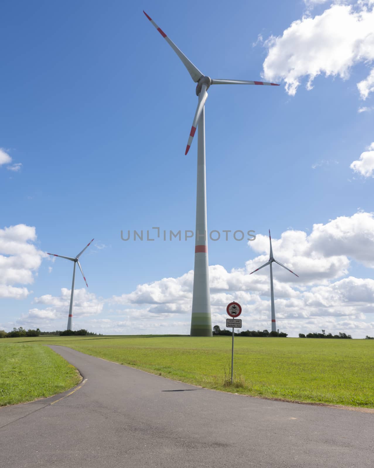 wind turbines in german eifel in green grass with blue sky and white clouds on sunny summer day