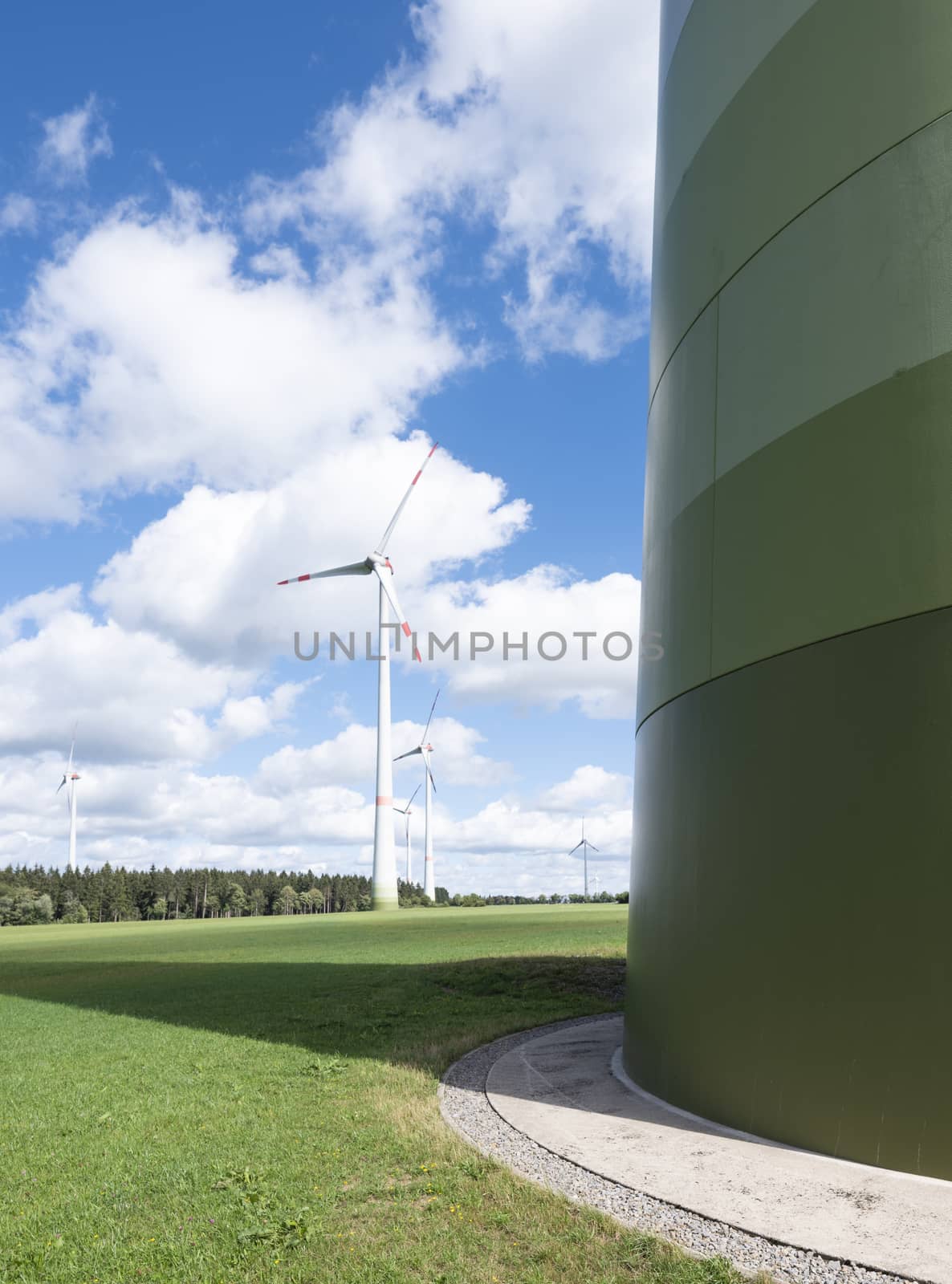 wind turbines in german eifel in green grass with blue sky and white clouds by ahavelaar