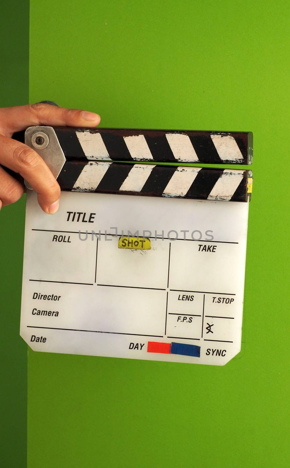 Movie slate board or clapper board and man hand and white color and green screen background in studio.