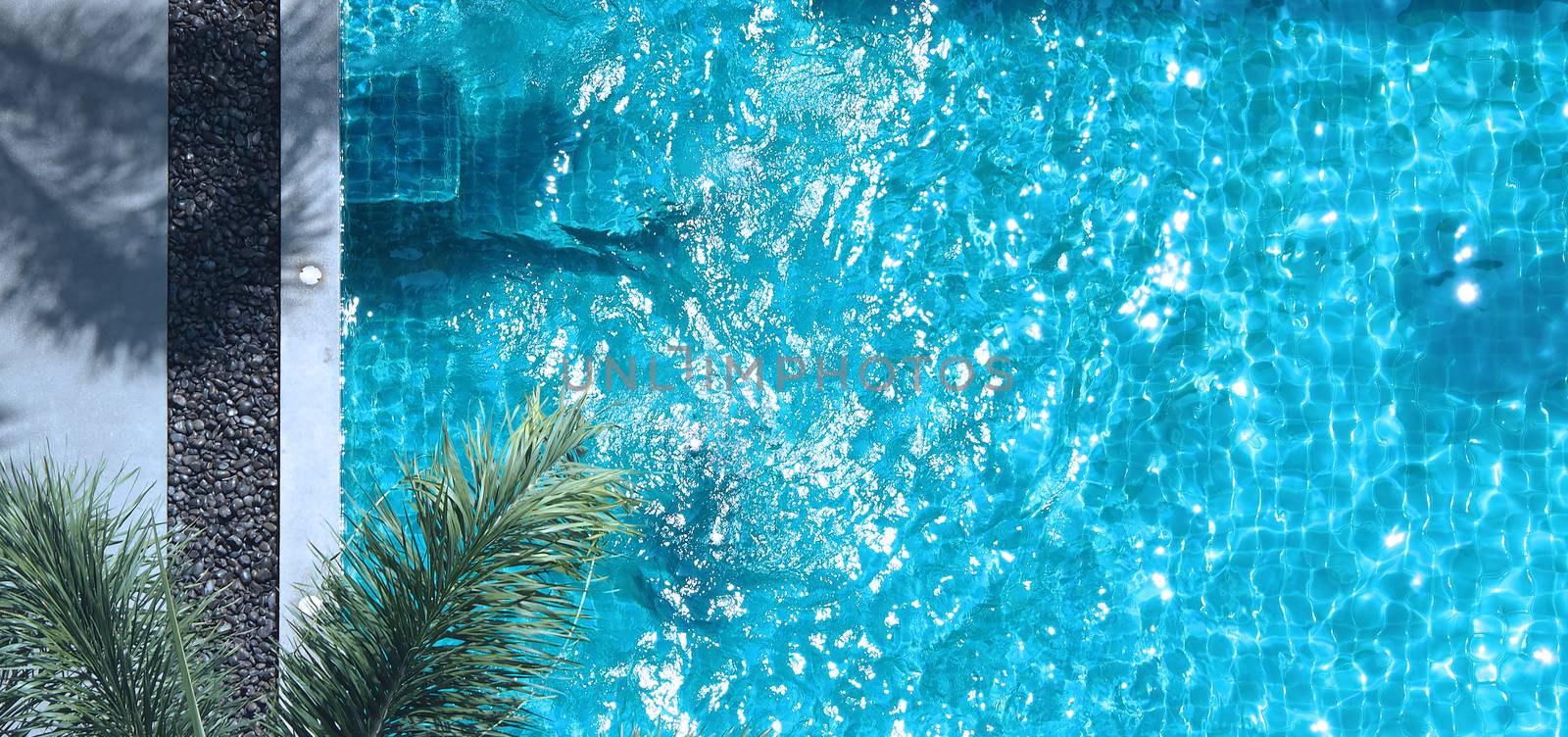 Swimming pool blue water in summer and white beach beds and top view angle.