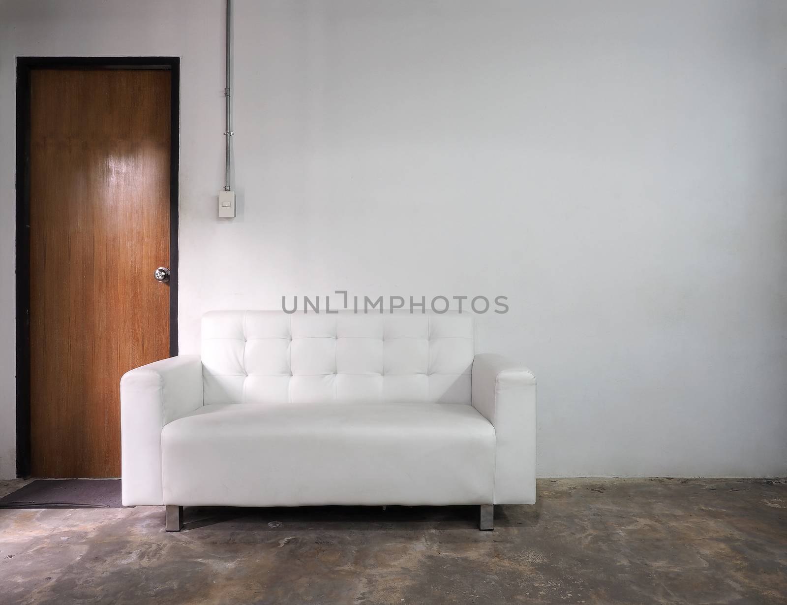 White leather sofa and white old wall and old wood door in room.
