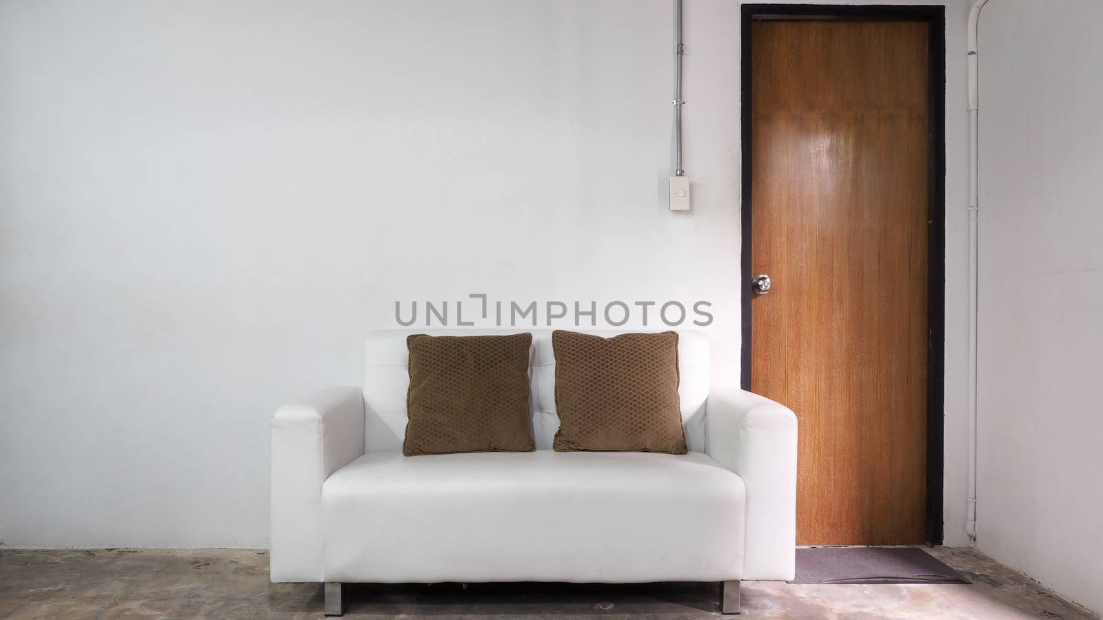 White leather sofa and white old wall and old wood door in room.