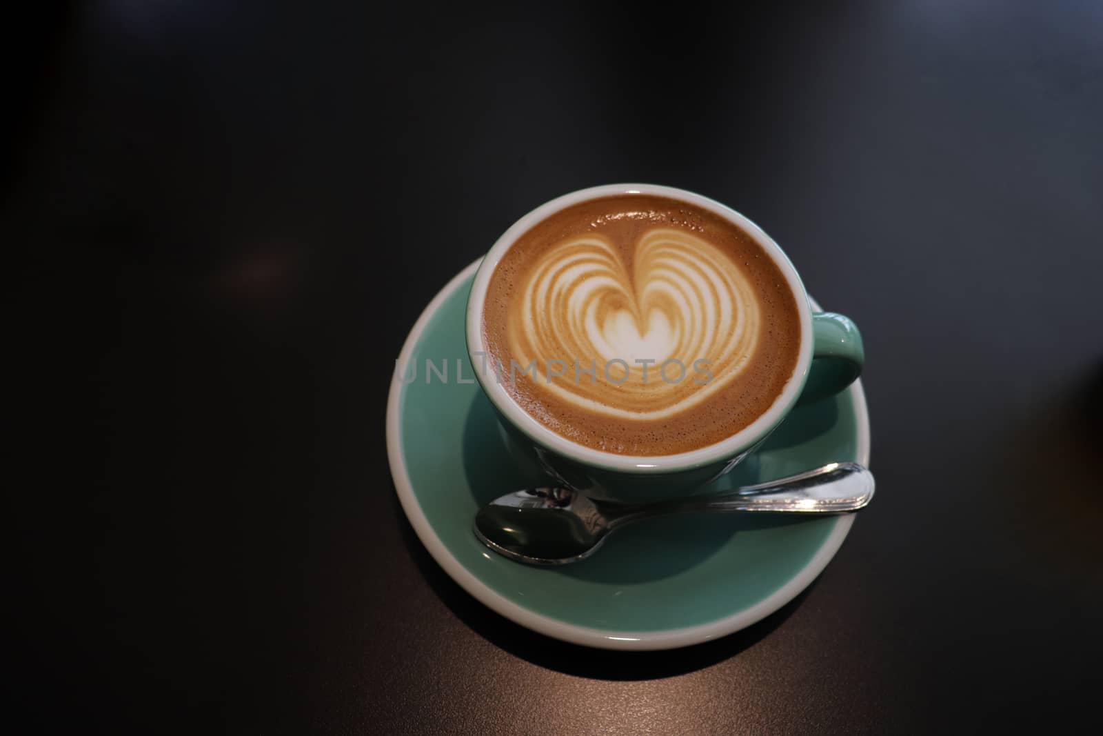 Spoon and cup of coffee on black background by uphotopia