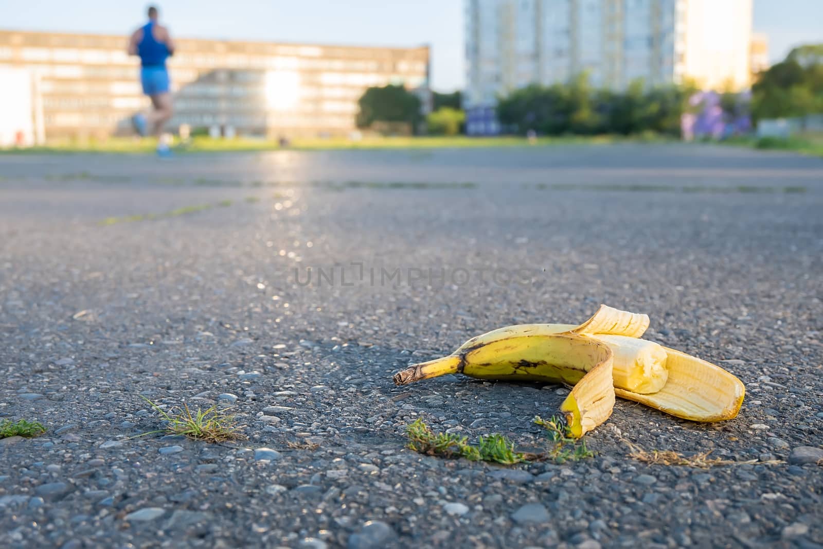 a discarded bitten banana is lying on the running track of the stadium, where athletes run past