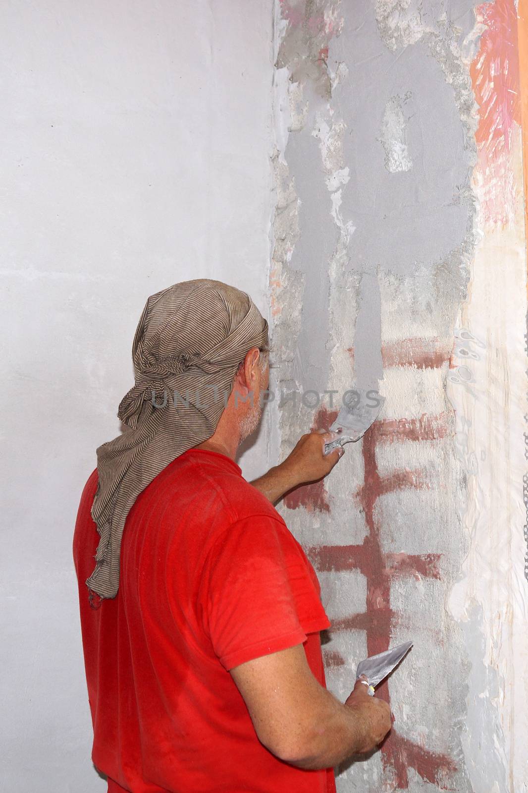 man plastering a crack in the wall close up by Annado